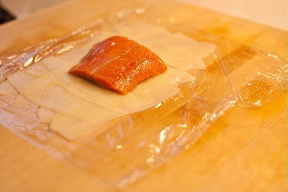 Using plastic wrap, you can wrap the potato slices around the salmon.